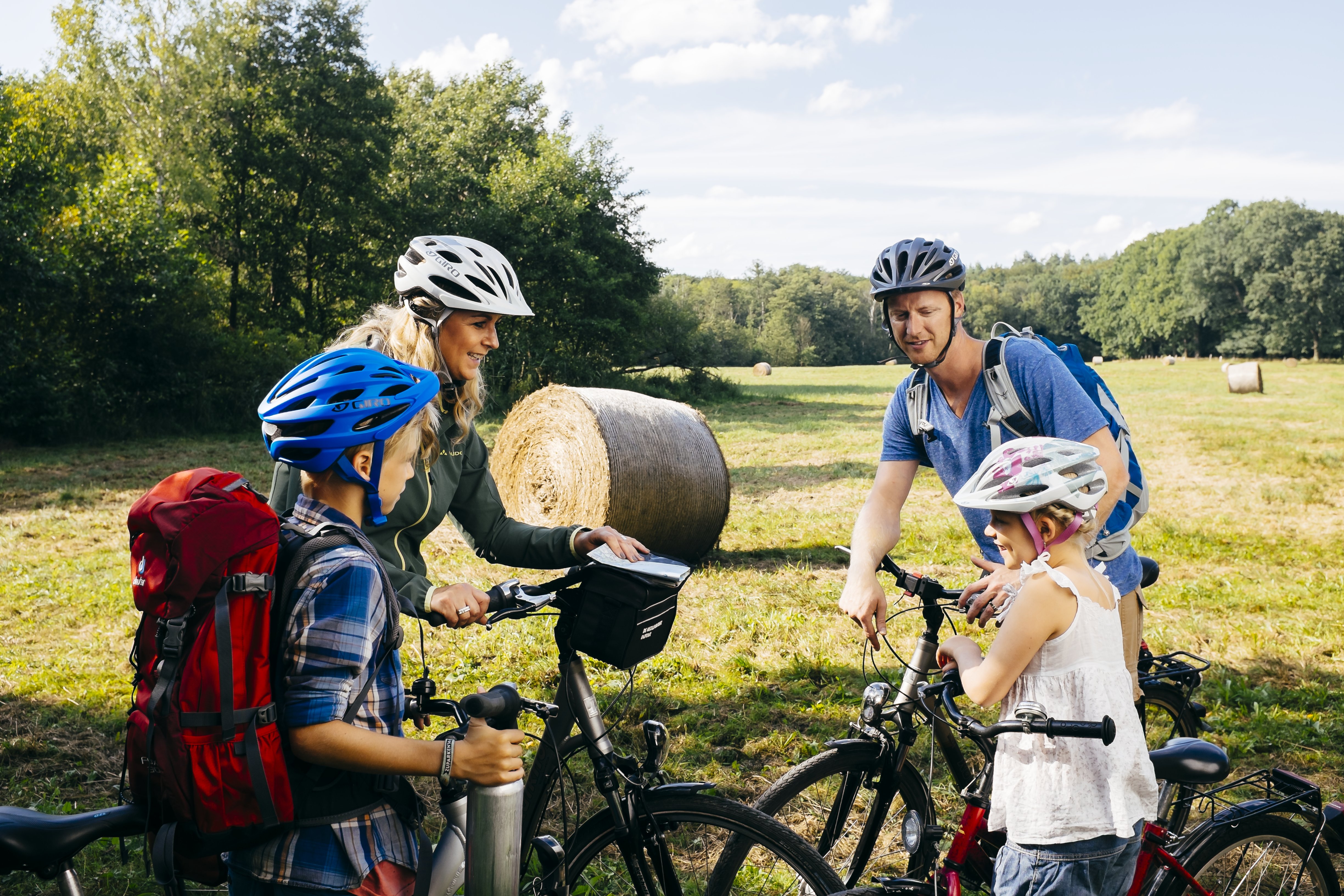 Eine Familie steht mit ihren Fahrräder am Rand eines Feldes und berät sich.